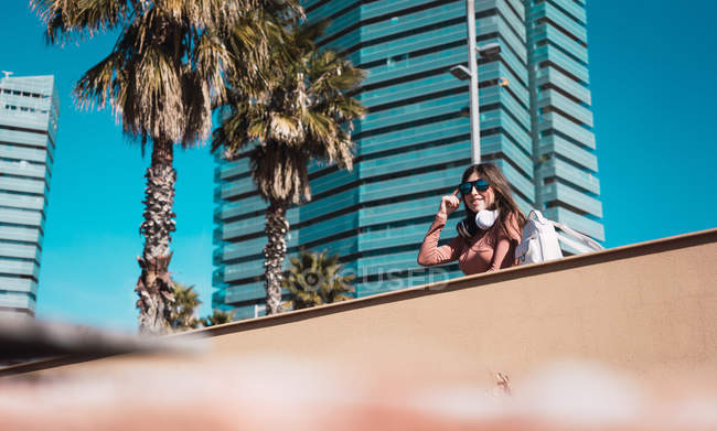 Chica adolescente mirando la calle mientras escucha música con sus cascos y su teléfono inteligente - foto de stock