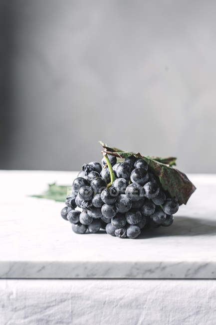 Bouquet de raisins avec feuilles sur la table — Photo de stock