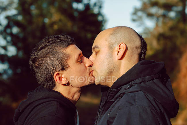 Casal homossexual beijando no caminho na floresta no dia ensolarado — Fotografia de Stock