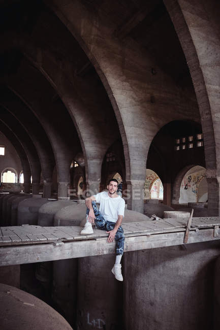 Чоловік сидить на мосту всередині старої будівлі — стокове фото