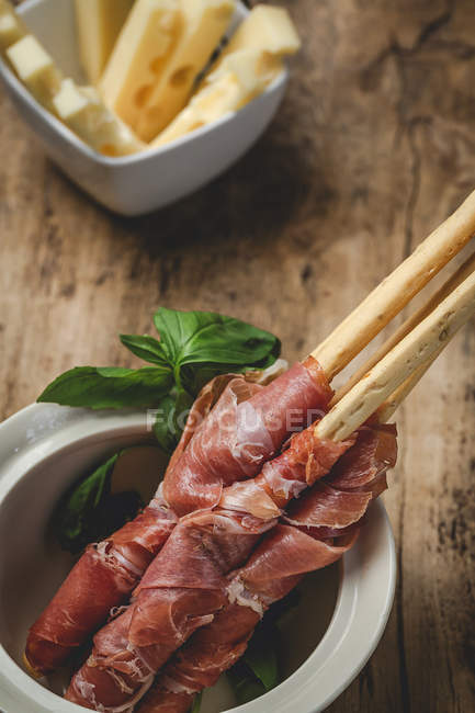 Gressinis with spanish typical serrano ham in pot on wooden table with cheese — Stock Photo