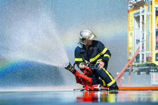 Anonymous fireman fighting fire with water — Stock Photo