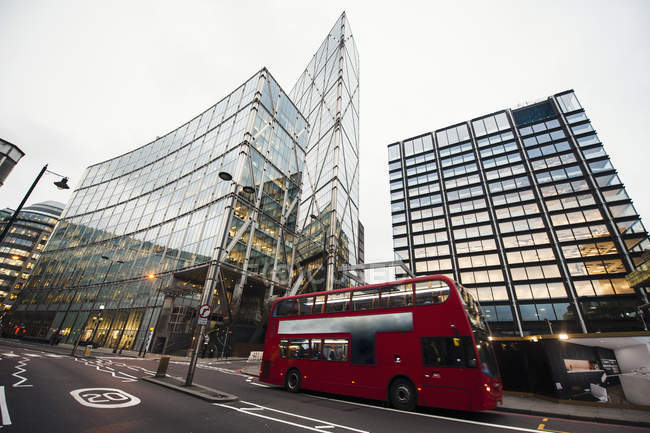 Roter Bus auf der Straße in der Nähe beleuchteter moderner Gebäude auf der Straße von London — Stockfoto