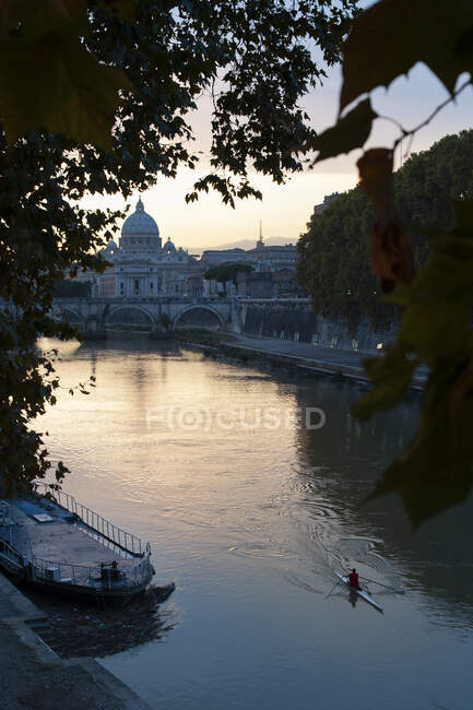 Persona irriconoscibile che galleggia su una piccola barca verso il meraviglioso Ponte Garibaldi durante il tramonto a Roma — Foto stock