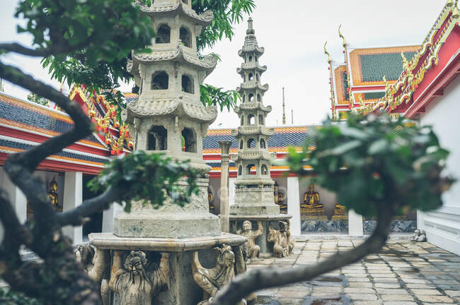 Green plants and ornamental shrines decorating yard of beautiful oriental temple in Thailand — Stock Photo