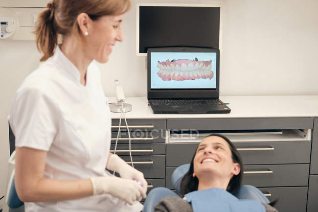 Dentiste démontrant le balayage des dents sur l'écran d'ordinateur portable au petit garçon dans la clinique moderne — Photo de stock