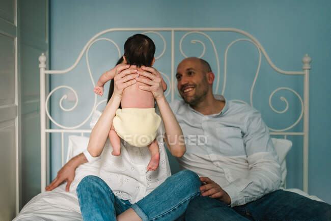 Батьки обіймають дитину на ліжку. — стокове фото