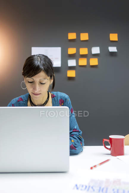 Businesswoman working on laptop while sitting at desk in modern office — Stock Photo