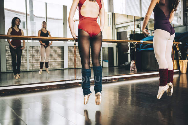 Frauen in Ganzkörperanzügen springen beim Balletttraining im Studio auf Spitze über dem Boden. — Stockfoto