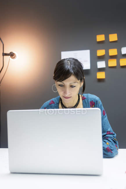 Focused businesswoman working on laptop while sitting at desk in modern office — Stock Photo