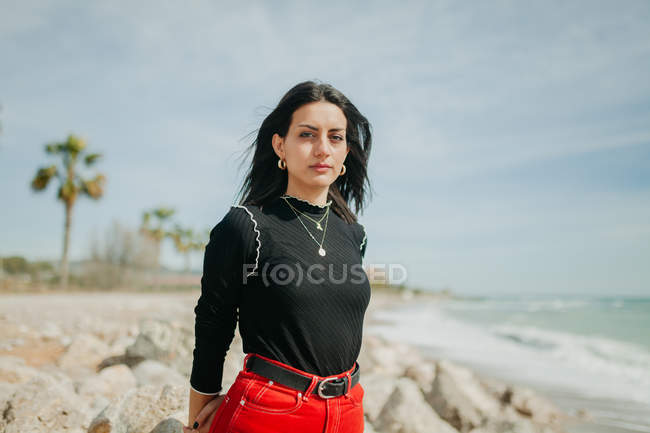 Sensual woman looking at camera while standing on sunny beach — Stock Photo