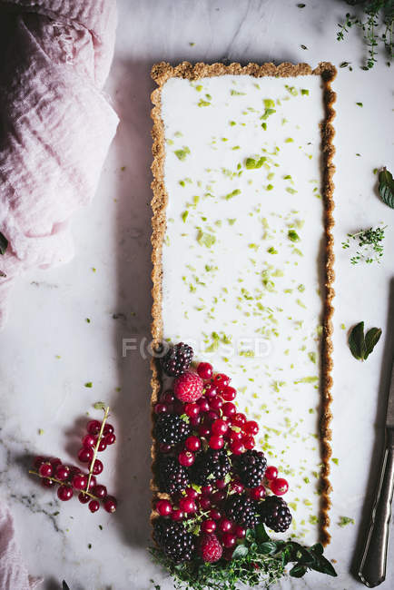 Lime pie with fresh berries on white marble surface — Stock Photo