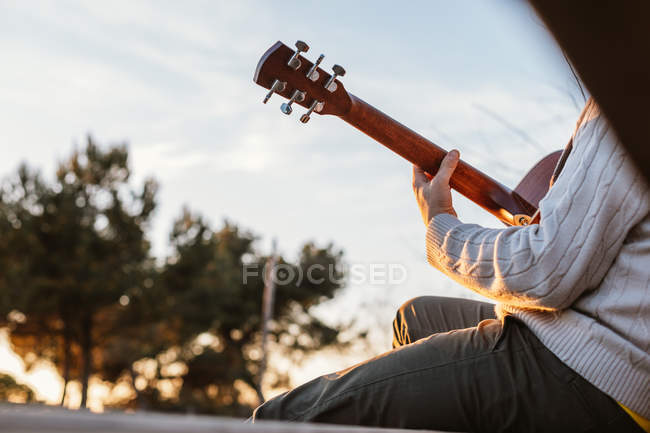 Крупним планом людина грає на гітарі в сільській місцевості на заході сонця — стокове фото