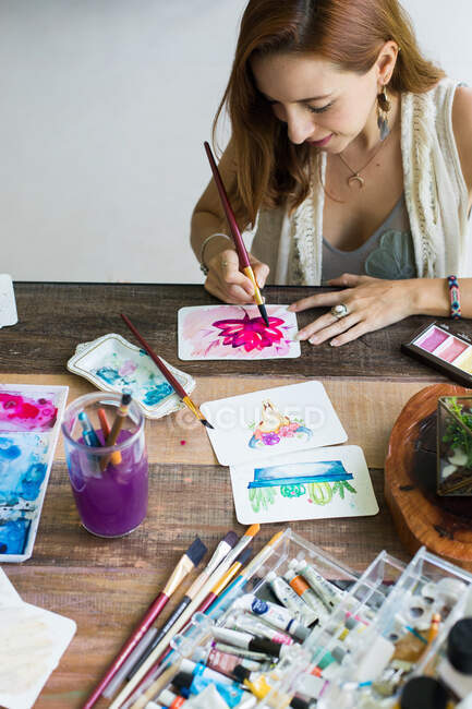 Latin artist painting with watercolor in her studio — Stock Photo