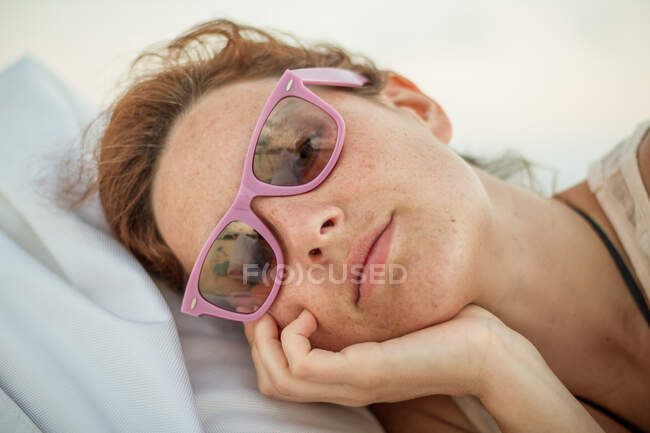 Mulher bonita em tons da moda olhando para a câmera enquanto deitado em saco de feijão macio no dia ensolarado em Maldivas — Fotografia de Stock