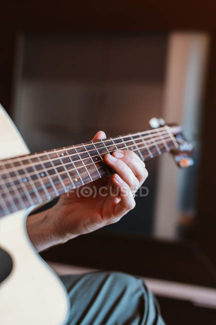 Mão de homem tocando guitarra em fundo embaçado — Fotografia de Stock