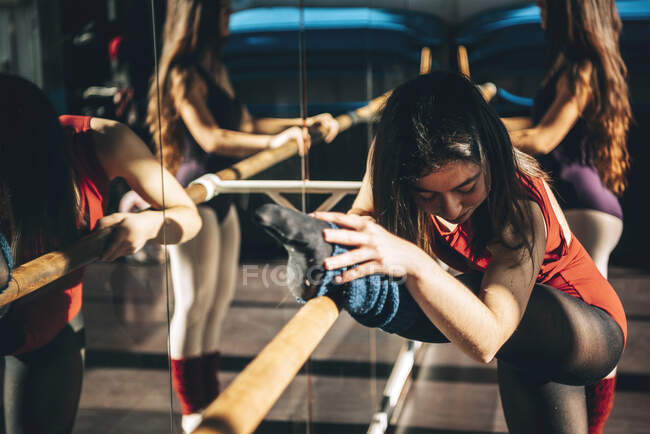 Bailarines de ballet concentrados entrenando con barra delante del espejo en el estudio. - foto de stock