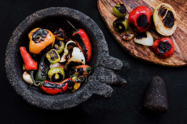 Delicious roasted vegetables in mortar and on wooden board — Stock Photo
