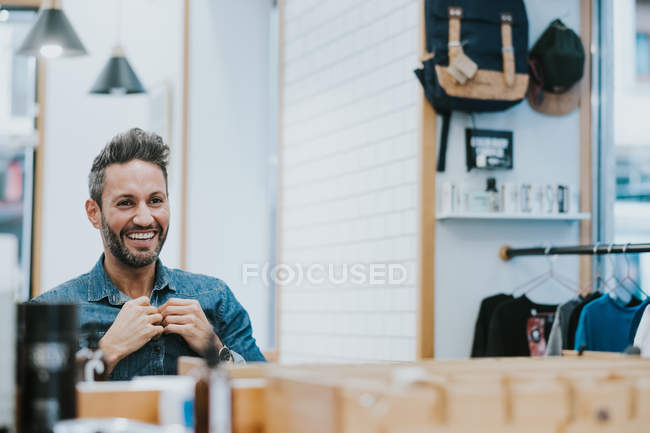 Reflection in mirror of handsome stylish male checking beard in salon — Stock Photo