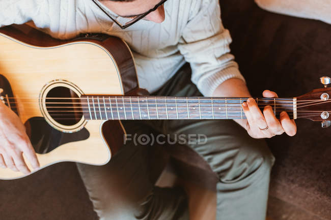 Primer plano del hombre tocando la guitarra sobre fondo oscuro - foto de stock
