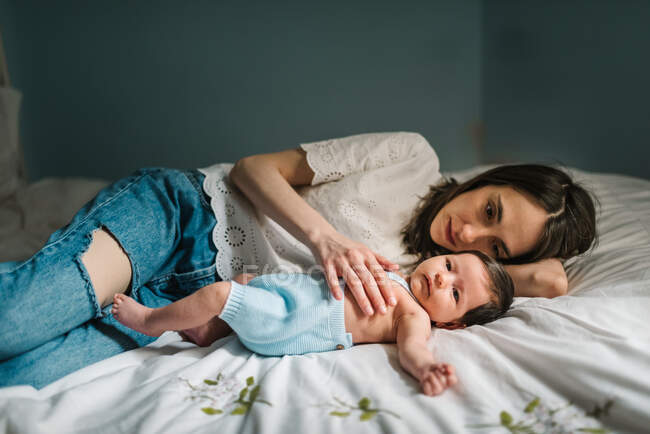 Madre y bebé acostados en la cama - foto de stock