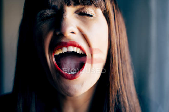 Attractive female with mouth open and red lips kissing clean transparent glass passionately — Stock Photo