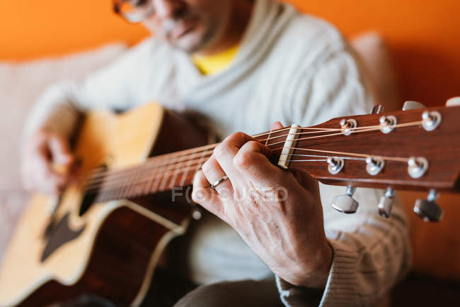Крупним планом людина грає на гітарі на помаранчевому фоні — стокове фото