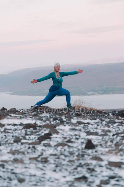 Femme blonde faisant de l'exercice sur la rive enneigée dans la nature — Photo de stock