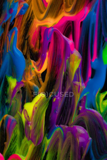 Derrames de pigmento grueso de varios colores mezclando sobre fondo negro - foto de stock