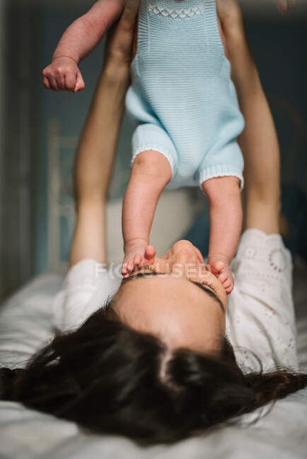 Madre jugando con el bebé en la cama - foto de stock