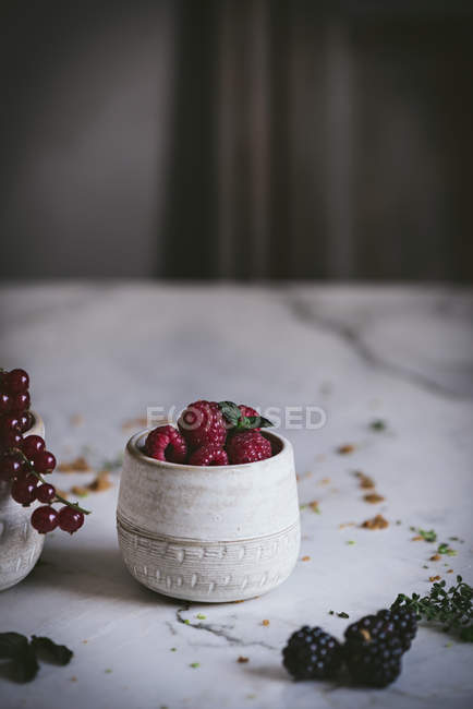 Fresh summer berries in cups on white marble surface — Stock Photo