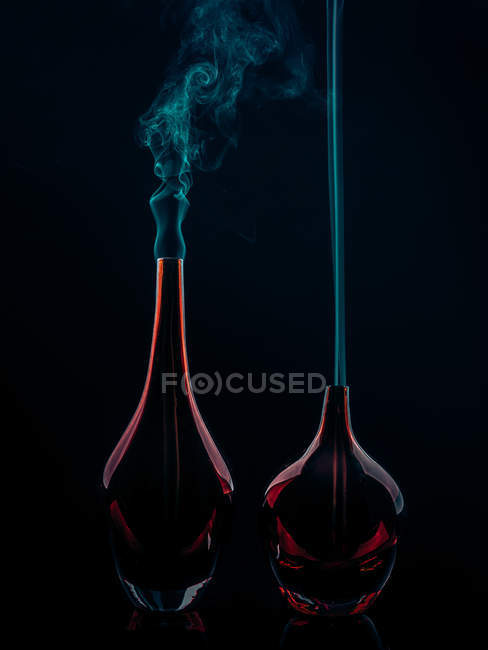 Glasflaschen mit Rauch auf schwarzem Hintergrund — Stockfoto