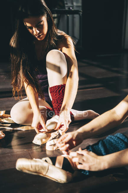 Bailarinas em estúdio preparando e colocando sapatos de cetim pointe. — Fotografia de Stock