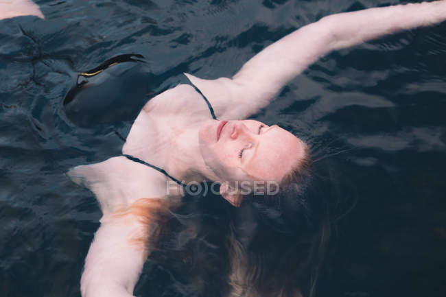 Nahaufnahme einer ruhigen Frau, die sich im Wasser des Pools entspannt — Stockfoto