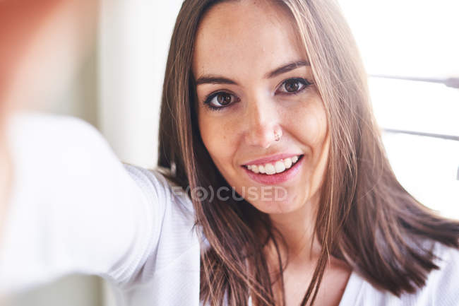 Portrait of young happy woman in front window — Stock Photo