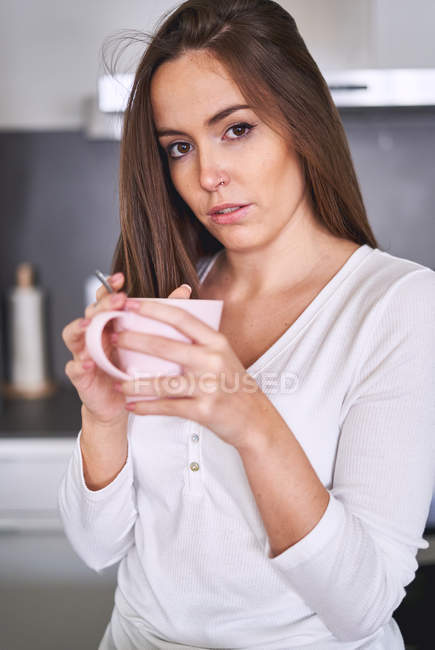 Портрет молодой женщины, держащей кружку на современной кухне дома — стоковое фото