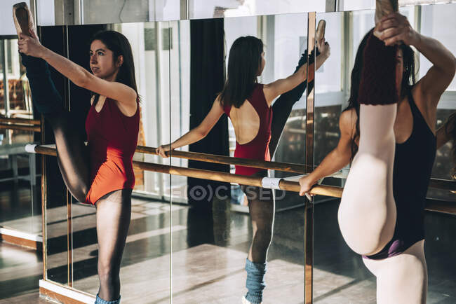 Les jeunes ballerines flexibles s'entraînent dans un studio ensoleillé et étirent leurs muscles. — Photo de stock