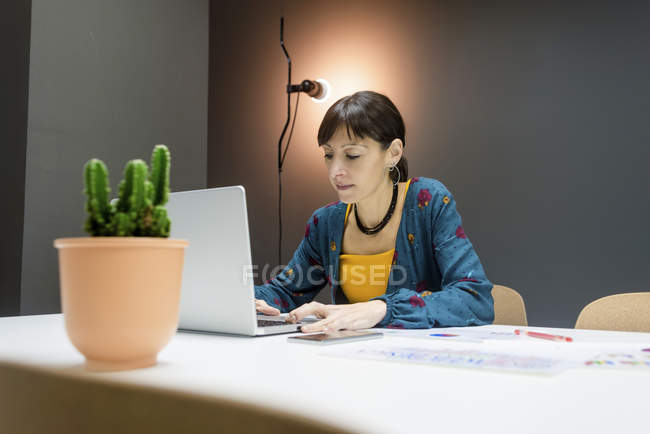 Empresária trabalhando no laptop enquanto sentado na mesa no escritório — Fotografia de Stock