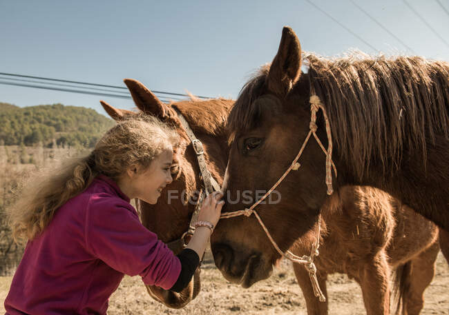 Femme prenant soin du cheval près de l'écurie après la leçon le jour ensoleillé sur le ranch — Photo de stock