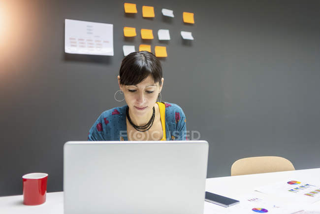 Деловая женщина, работающая на ноутбуке, сидя за столом в современном офисе — стоковое фото