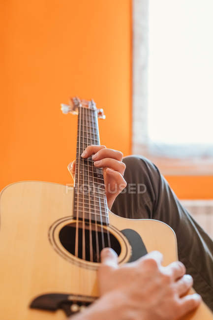 Manos del hombre tocando la guitarra en la cama - foto de stock