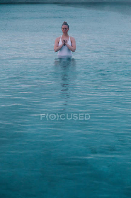 Giovane donna che medita in acqua di grande piscina — Foto stock