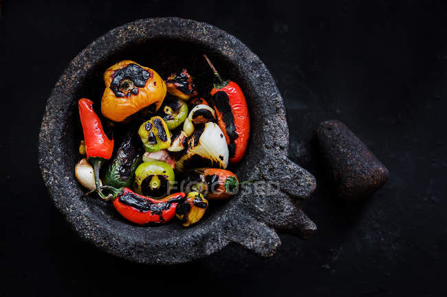 Deliciosos legumes assados em argamassa no fundo preto — Fotografia de Stock