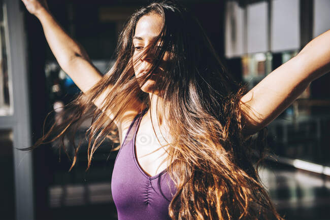 Junge Brünette mit langen wehenden Haaren bewegt sich beim Tanzen im Sonnenlicht. — Stockfoto