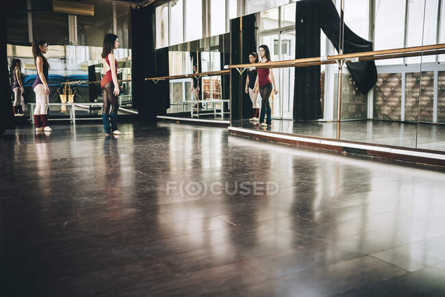Two young ballerinas in front of big wall mirror training together in studio. — Stock Photo