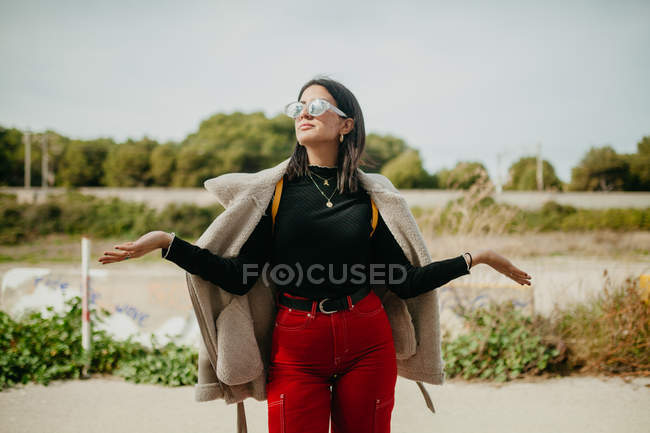 Sorrindo jovem mulher na roupa da moda com jaqueta posando no fundo borrado da costa — Fotografia de Stock