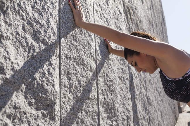 Femme brune penchée sur le mur après l'entraînement le jour ensoleillé — Photo de stock