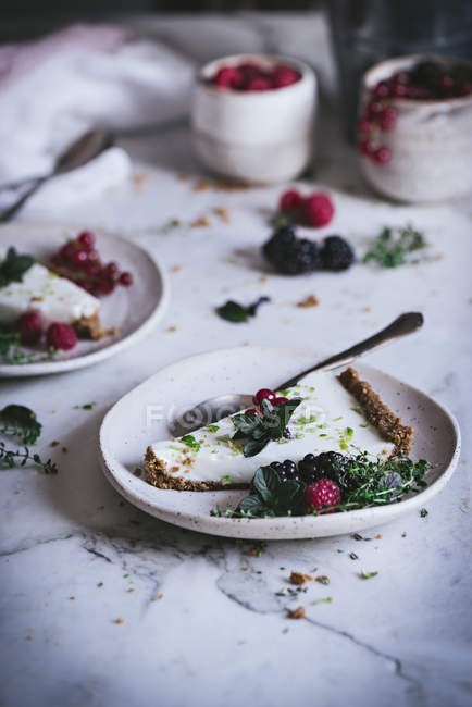 Кусочек лаймового пирога со свежими ягодами на тарелке на поверхности белого мрамора — стоковое фото