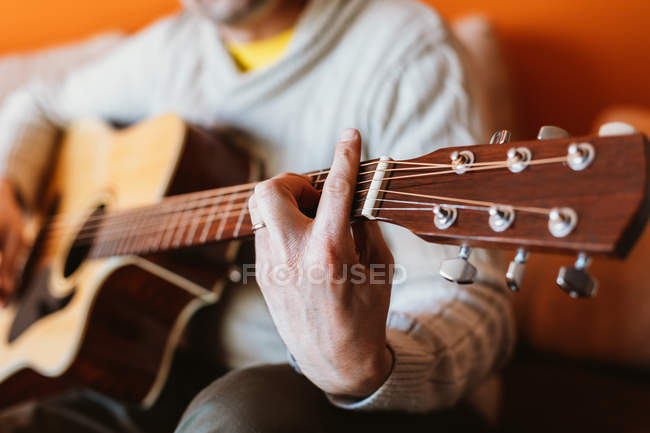Primer plano del hombre tocando la guitarra sobre fondo naranja - foto de stock