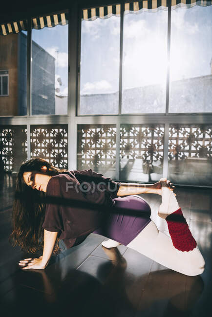 Ballerina dancer warming up flexible body in sunny studio. — Stock Photo